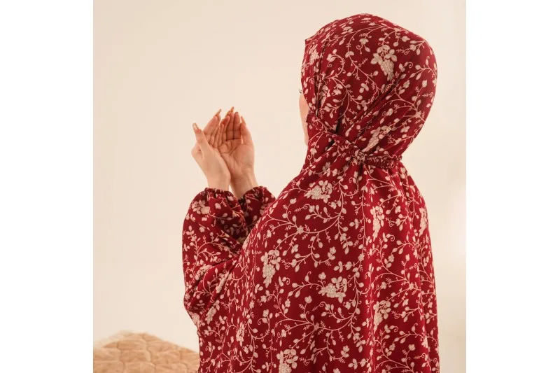 Kırmızı çiçek desenli tek parça namaz elbisesiyle dua eden kadın, arkadan